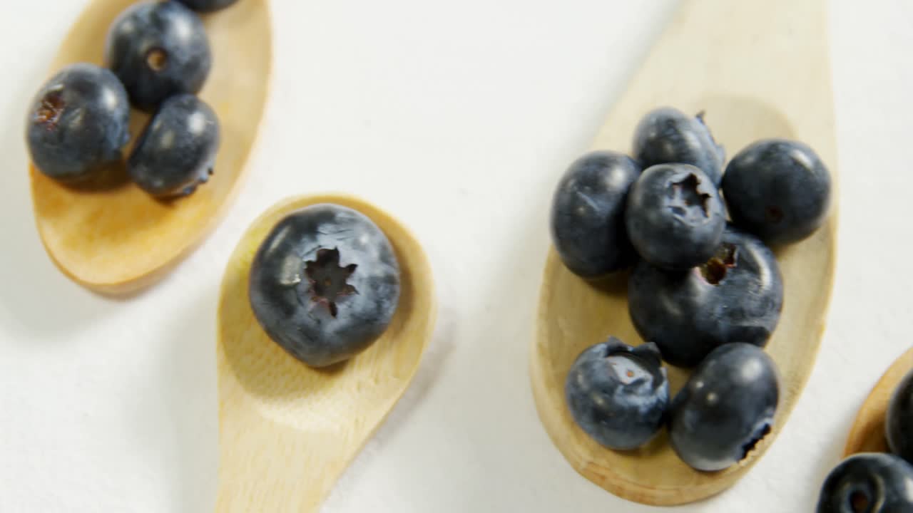 Blueberries in wooden spoon placed on white surface 4K 4k
