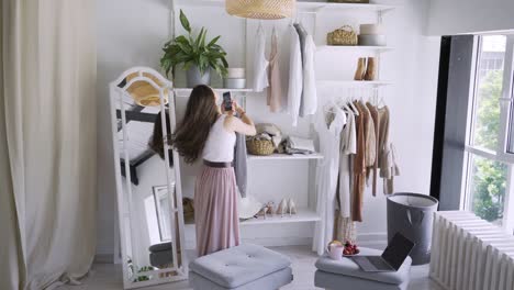 woman talks on phone choosing elegant clothes in wardrobe