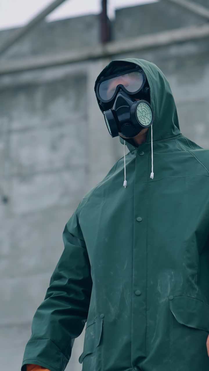 Man in gas mask on destroyed building background. Survivor in respirator and safety suit standing in radioactive zone. Ecological catastrophe. Post apocalyptic world. Vertical video