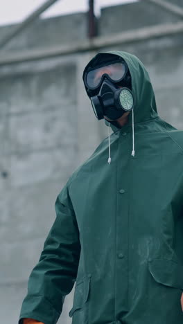 man in gas mask on destroyed building background. survivor in respirator and safety suit standing in radioactive zone. ecological catastrophe. post apocalyptic world. vertical video