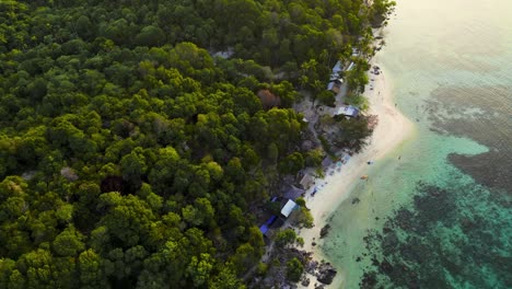 aerial-view-looking-down-to-Tanjung-Gelam,-a-beach-with-white-sand-and-turquoise-water-surrounded-by-forest---Karimunjawa,-Central-Java---Indonesia