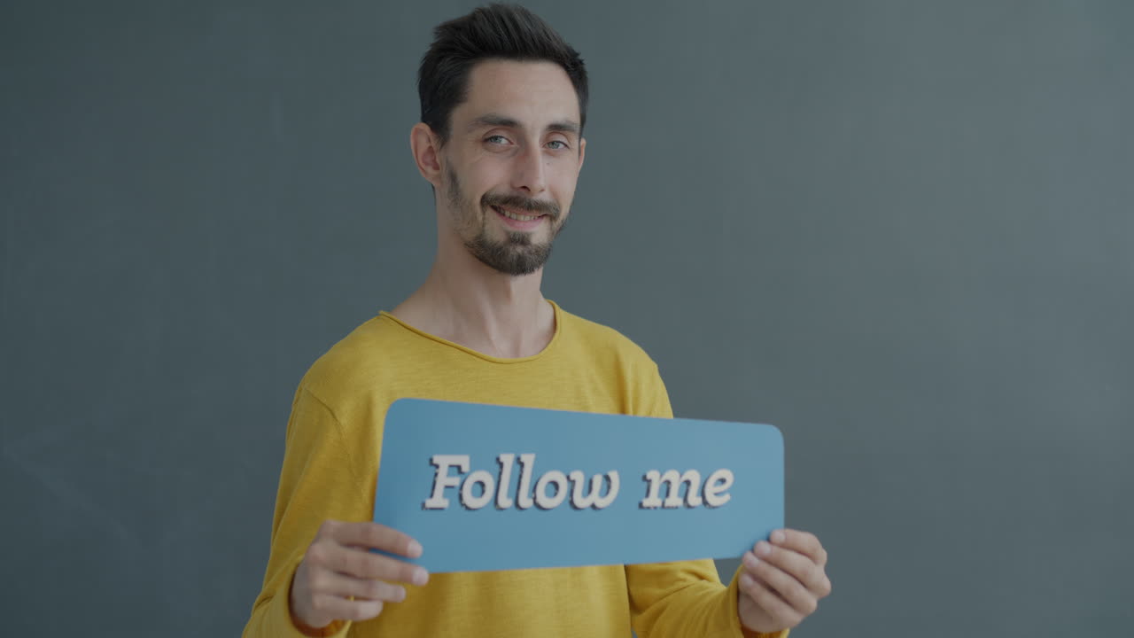Uomo che regge un cartello con la scritta "Seguimi"