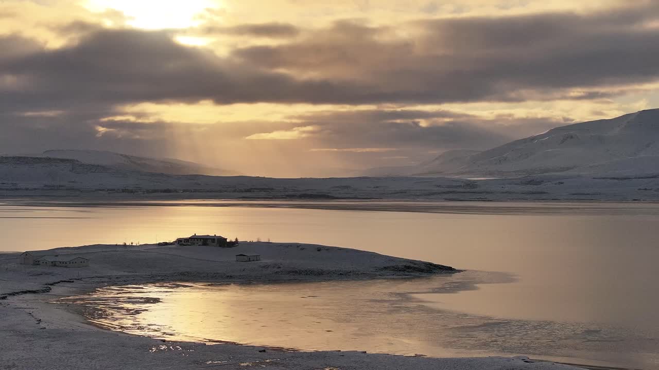 Golden winter sunset over a snowy peninsula in Borgarfjörður bay, Iceland.