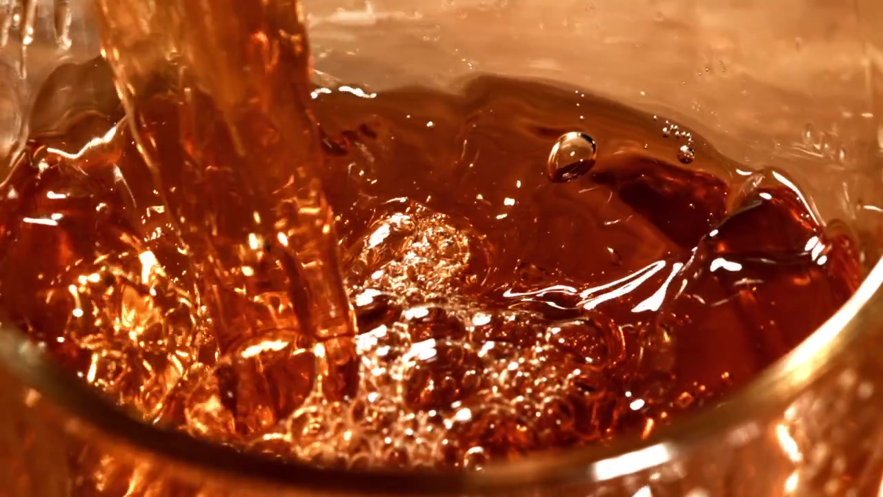 Primo piano di rinfrescante liquido ambrato che si versa in un bicchiere