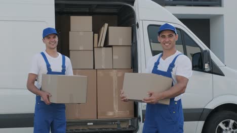 two young workers of removal company unload boxes from minibus into customer's home