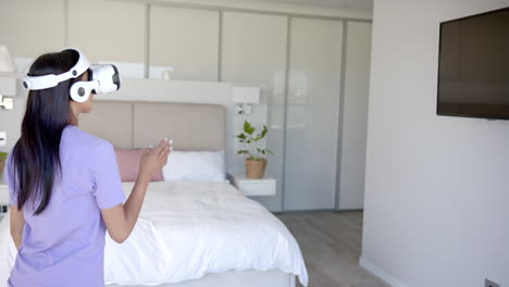 using vr headset, woman interacting with virtual environment in bedroom, copy space