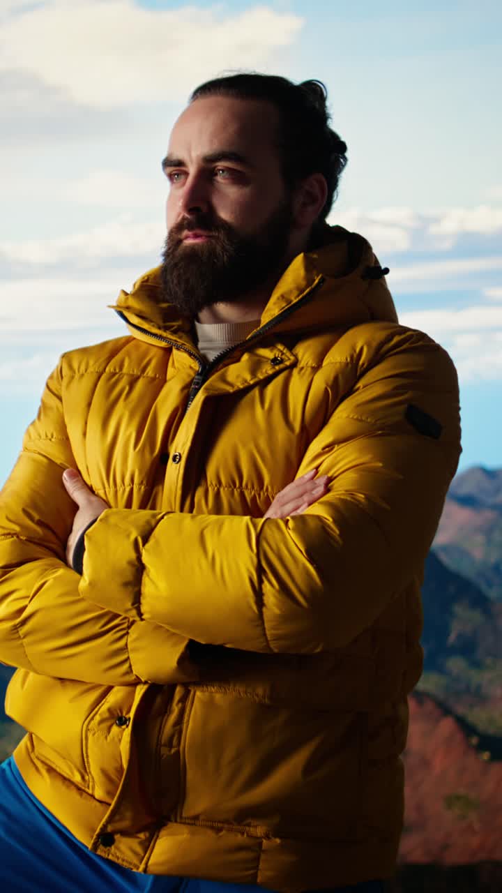 Bearded Man in Yellow Puffer Jacket Standing on Mountain Top