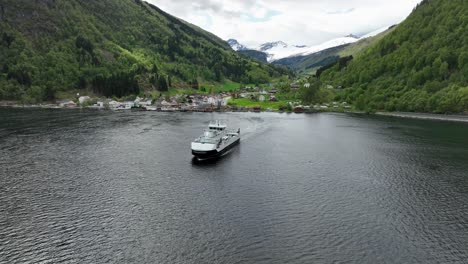 Die-Fähre-Haroy-Segelt-In-Richtung-Kamera,-Nachdem-Sie-Das-Idyllische-Dorf-Eidsdal-Verlassen-Hat-–-Luftaufnahme-über-Dem-Fjord-Mit-üppigem-Tal-Im-Hintergrund-–-Norwegen