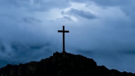 silhouetted cross stands on a hill as clouds move rapidly across the sky, creating a dramatic and inspirational scene