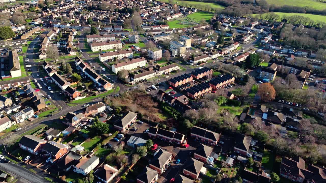 Aerial landscape drone shot over Sholing, a region in Southampton, England. A beautiful suburb with red homes, gardens, busy roads with traffic and cars during a beautiful winter sunset