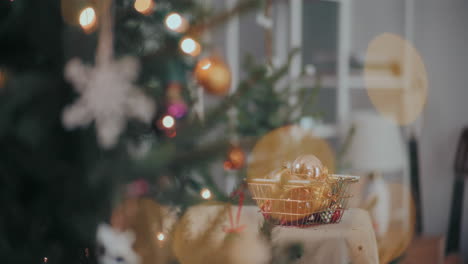 male hand picking bauble from basket at illuminated home during christmas