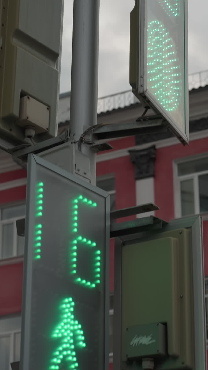 vista cercana de un semáforo digital que muestra una cuenta atrás. un edificio de la ciudad de color rojo es visible en el fondo bajo un cielo nublado