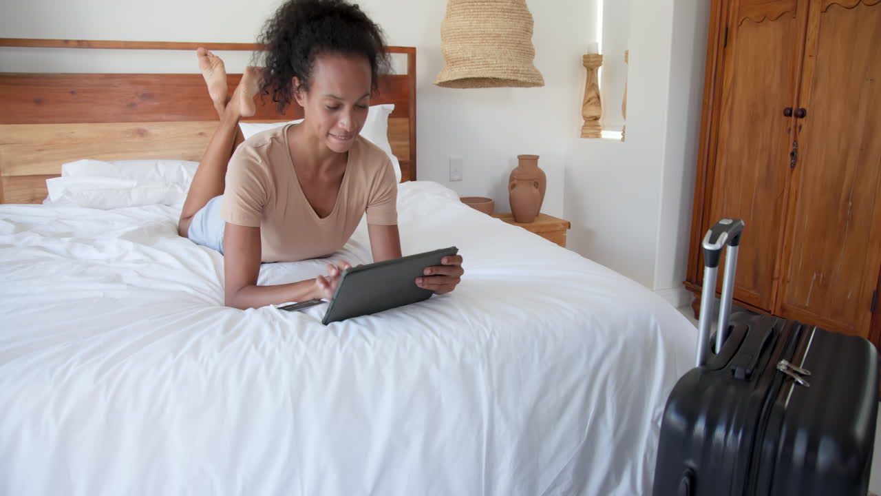woman relaxing on bed using tablet and smiling at home