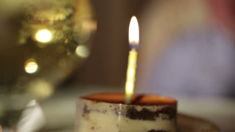 glass of champagne and candle in the tiramisu cake