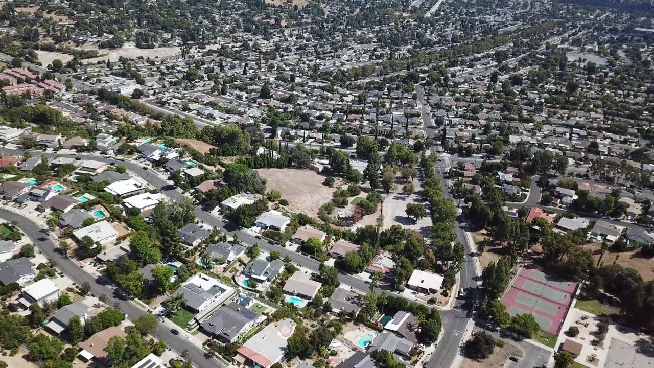 Aerial top down of upper class housing area in Hidden Hills with tennis fields. Sunny summer day in USA. Main street with villas and luxury homes. Flyover shot. Calabasas, LA, California. Wide shot