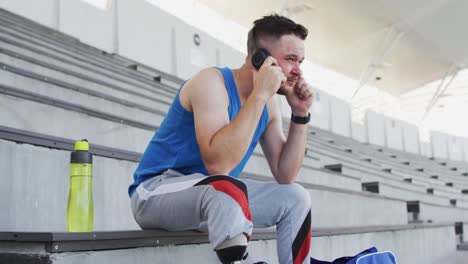 caucasian disabled male athlete with prosthetic leg sitting, wearing headphones