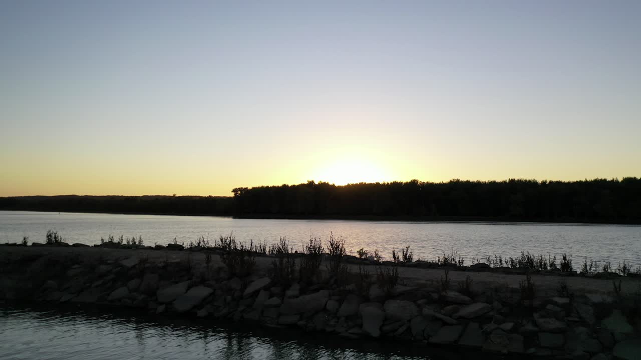 aerial fly over a lake side marina with pontoon and motor boats docked within the break water.