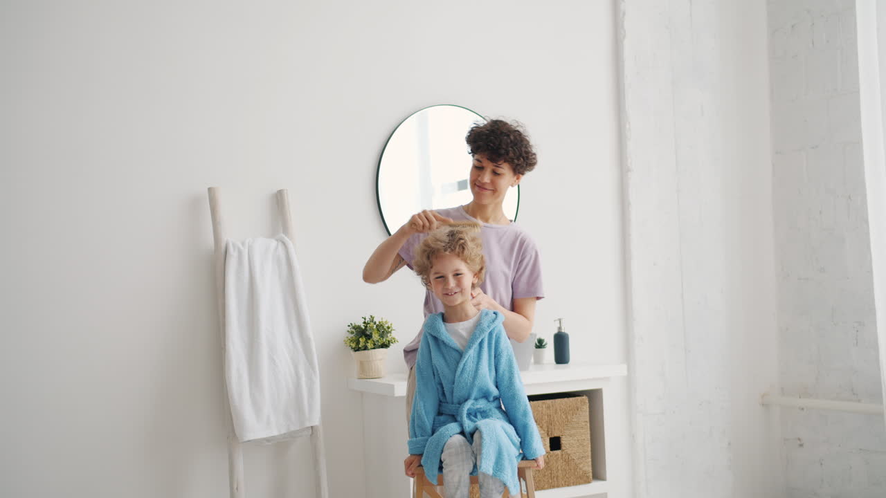 Mother brushing child's hair in bathroom