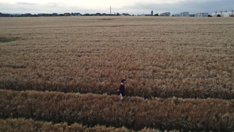 a man walking through a field near the city in the evening