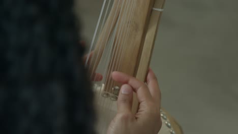 manos femeninas tocando arpa africana kora en un ambiente de luz de día cálido, primeros planos