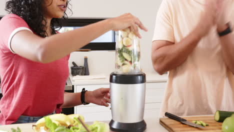 blending fruits, young multiracial couple preparing healthy smoothie in kitchen together, at home