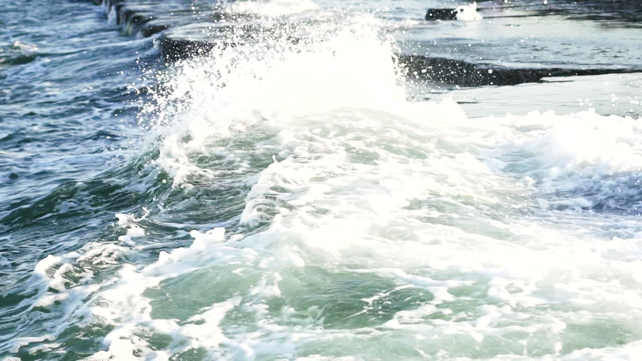 Wave and drops at the beach. Beautiful wave crashing on rocks in sea with big splash