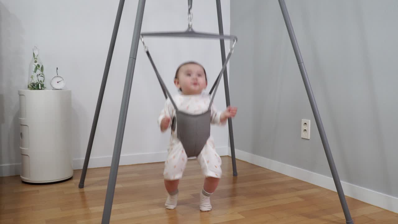 Un bambino bellissimo che si diverte un mondo a saltare in uno speciale saltatore fatto con una struttura in metallo e una molla sospesa.