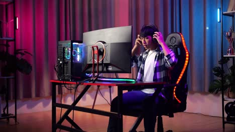 asian teen boy gamer wearing head phones and start play video game on computer