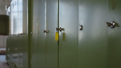 slow camera dolly back past green lockers with key in focus – moody industrial setting