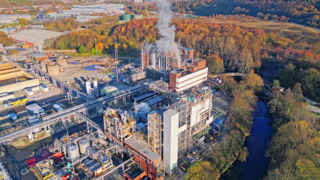 imágenes aéreas que avanzan hacia una gran planta química industrial, que muestran tuberías, estructuras metálicas, torres de refrigeración y almacenamiento de productos químicos