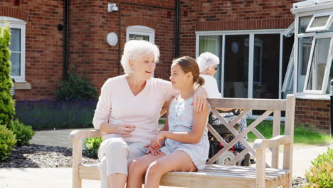 granddaughter sitting on bench with grandmother during visit to retirement home