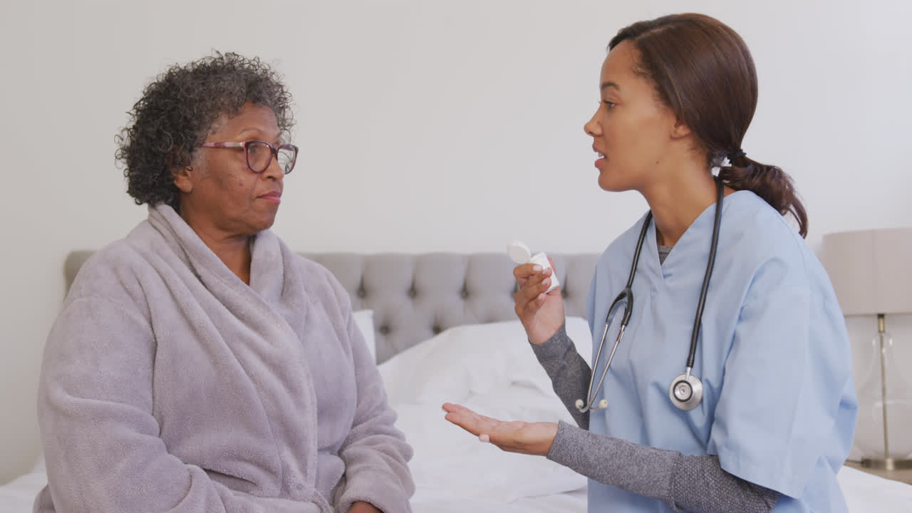 Femme métisse recevant la visite d'une infirmière à domicile. Distanciation sociale et auto-isolement en quarantaine.