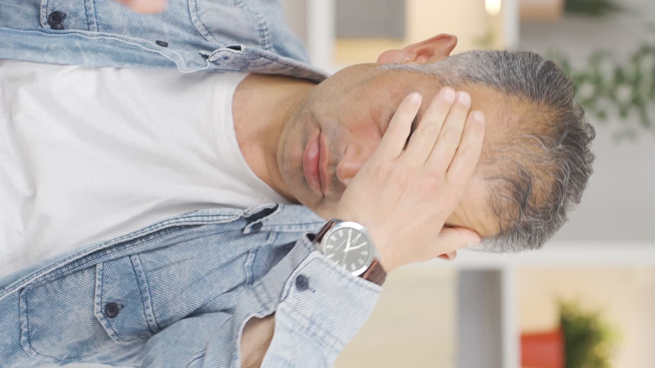 편두통을  ⁇ 고 있는 남자의 수직 비디오가 통증을 경험하고 있습니다.