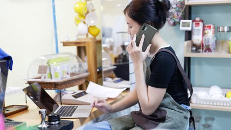 restaurant manager surfing the web and conversing on her smartphone at coffee shop .