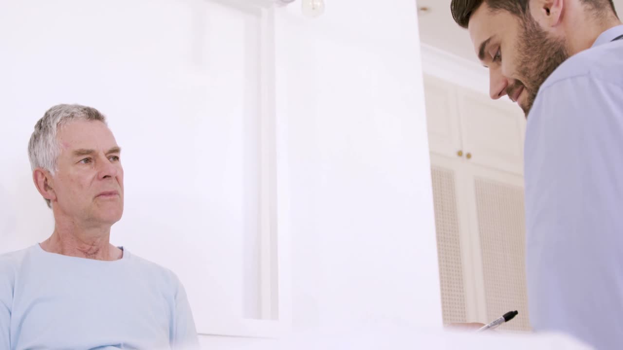 Male nurse talking with senior man in bed