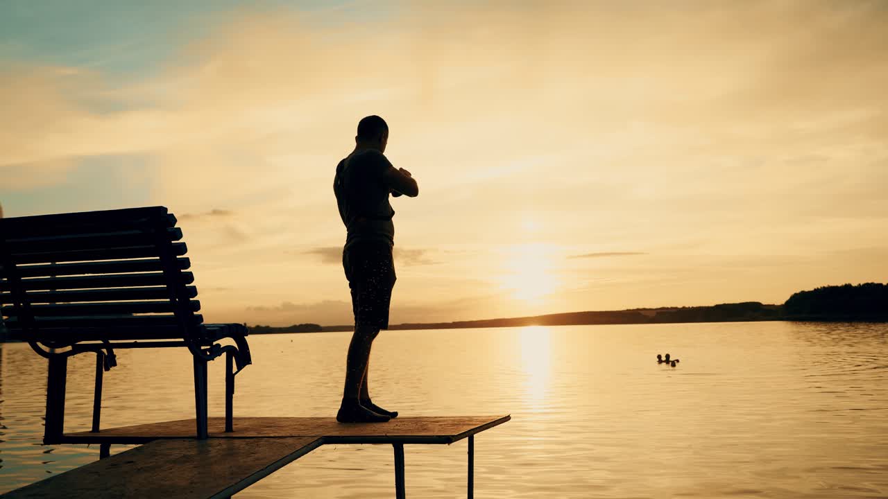 Photographer taking picture of landscape during sunset. Silhouette of people swimming in the river at sunset
