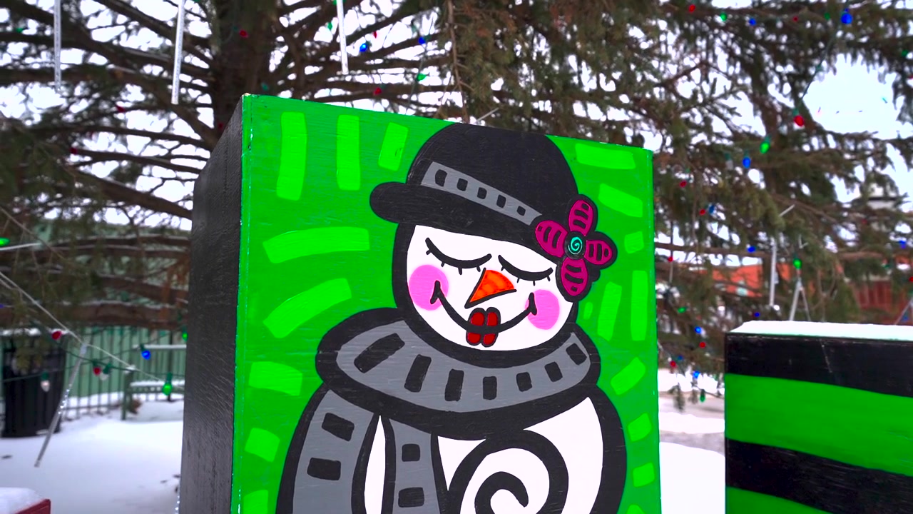 A festive snowman painting on a wall under a Christmas tree in Collingwood.