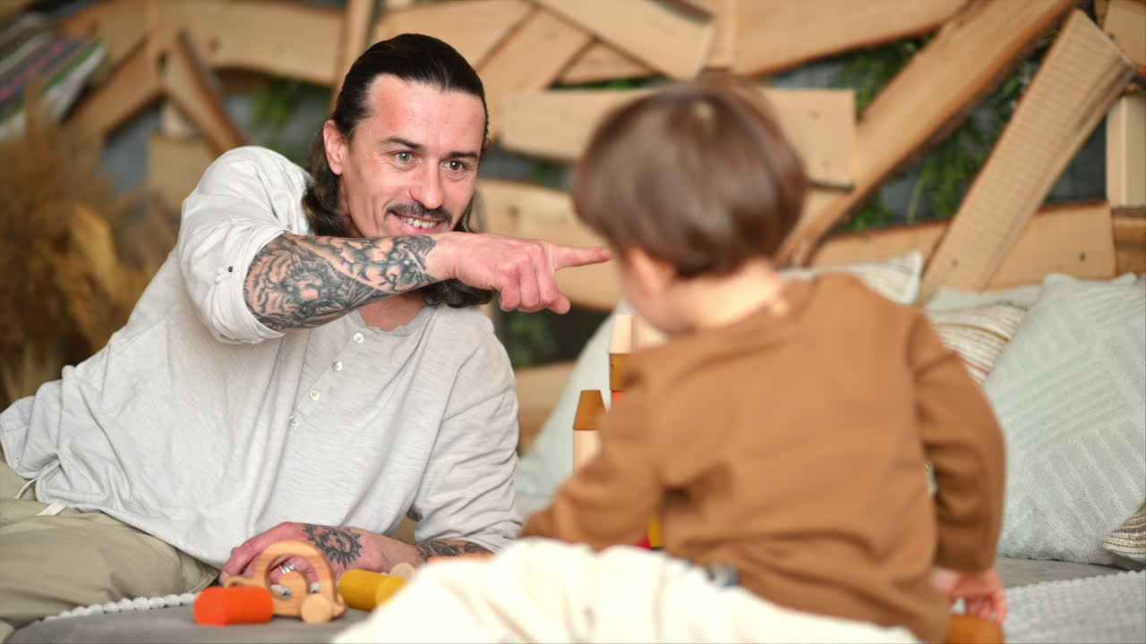 Padre jugando con su hijo con juguetes de madera ecológicos y coloridos en la cama