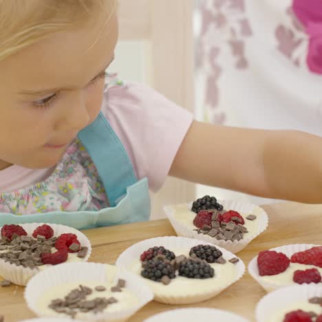 Süßes-Kleines-Mädchen,-Das-Beeren-Auf-Muffins-Setzt