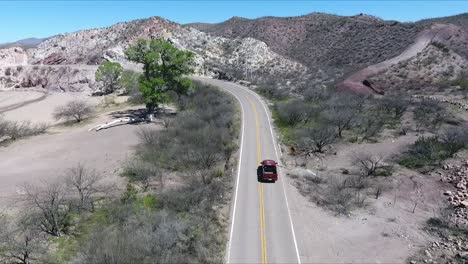 Drone-shot-following-a-lone-red-pick-up-truck-on-a-mountain-road-during-the-daytime