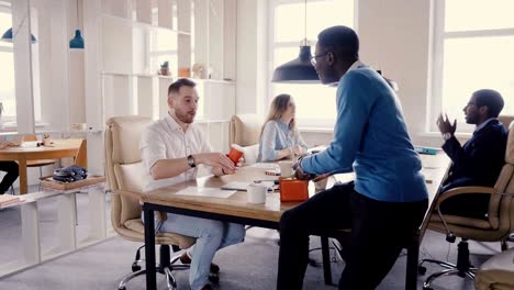 happy multiethnic colleagues talking in office. young mixed race business partners enjoy casual office atmosphere 4k