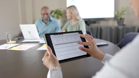 Diverse-business-people-using-laptop-and-tablet-at-conference-table-with-copy-space