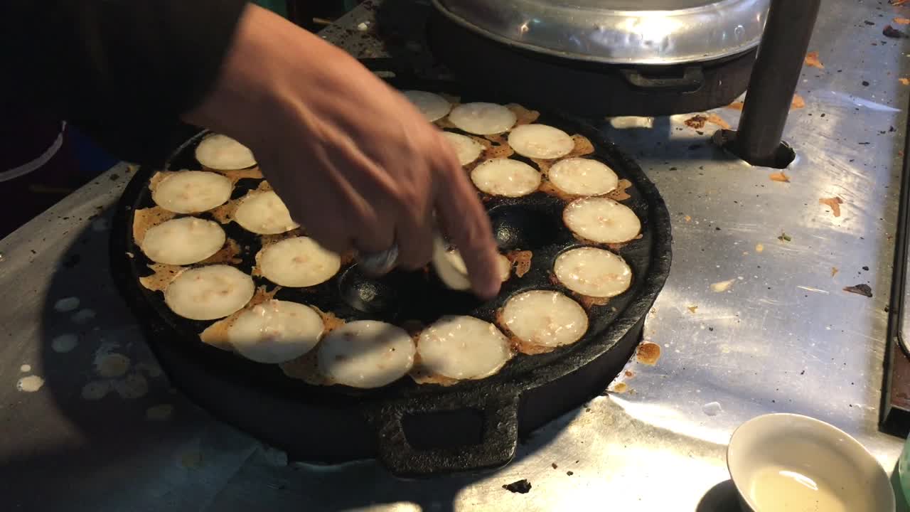 concepto de cocina. tipo de carne dulce tailandesa. leche de coco mezclada con postre frito en polvo en el mercado de comida callejera tailandés de la noche. postre de carne tradicional tailandesa, panqueque, pudín. imágenes de 4k.