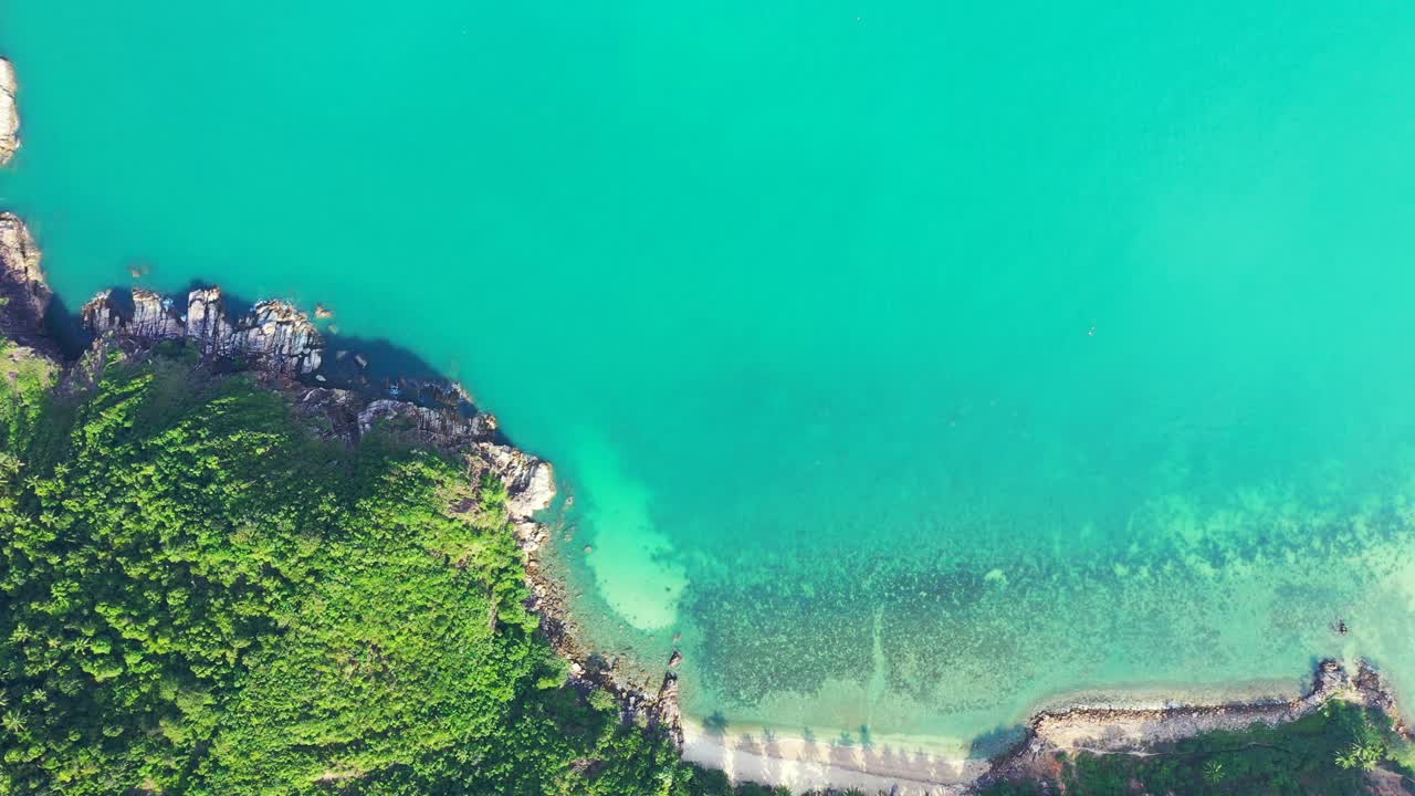 Peaceful bay with turquoise lagoon full of corals, washing sandy beach and rocky coastline of tropical island with lush vegetation in Vietnam