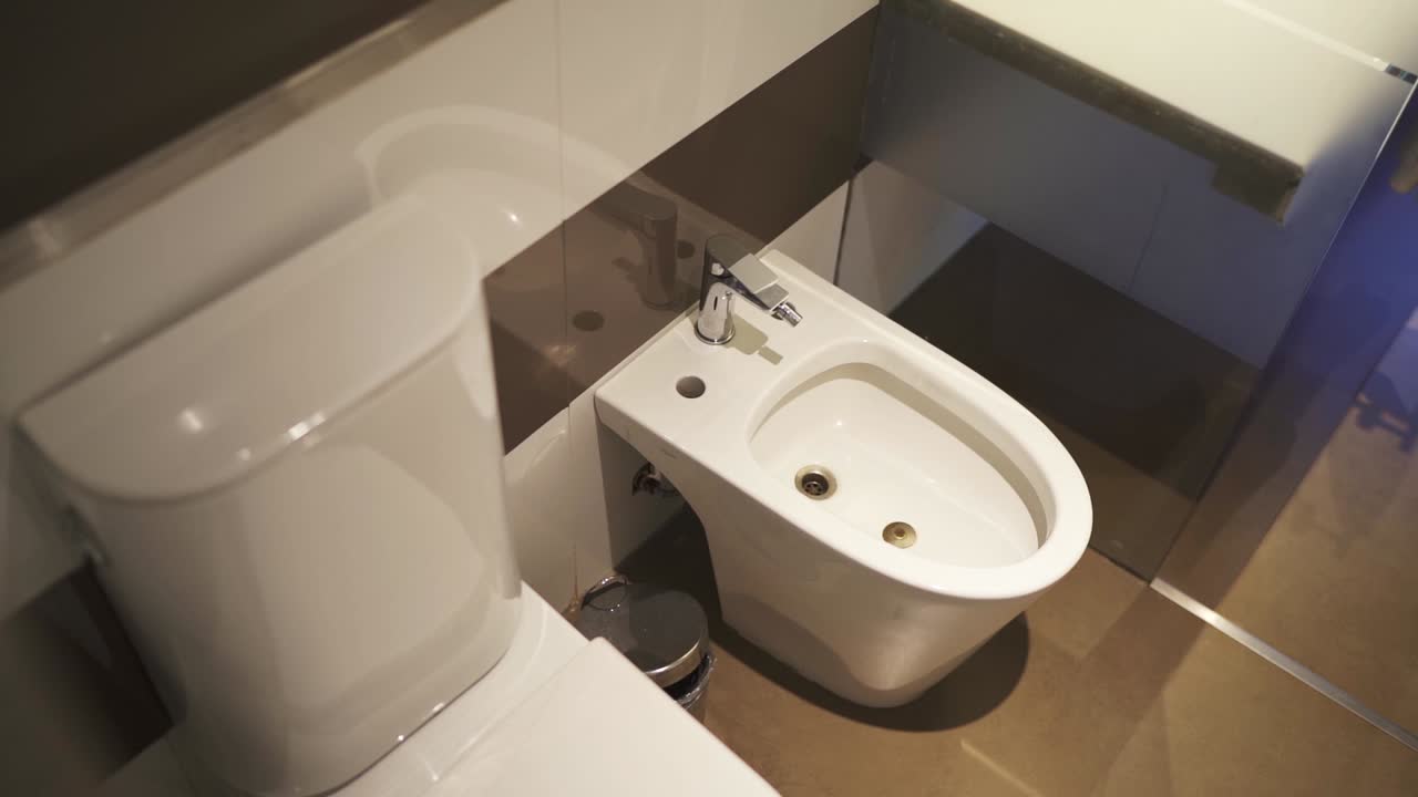 Contemporary hotel bathroom featuring a sleek toilet and bidet, showcasing clean lines, modern fixtures, and a minimalist aesthetic, emphasizing luxury and functionality