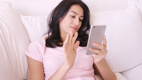 Woman-sitting-on-a-sofa-using-her-smartphone