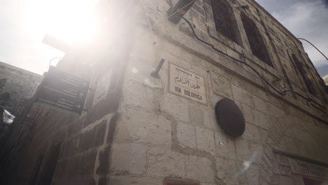 pivoting shot of the via dolorosa street sign marking where jesus christ carried the cross in jerusalem, israel.