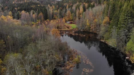 Scenic-drone-footage-of-a-forest-river,-mountain-cottage-and-hills-in-Autumn