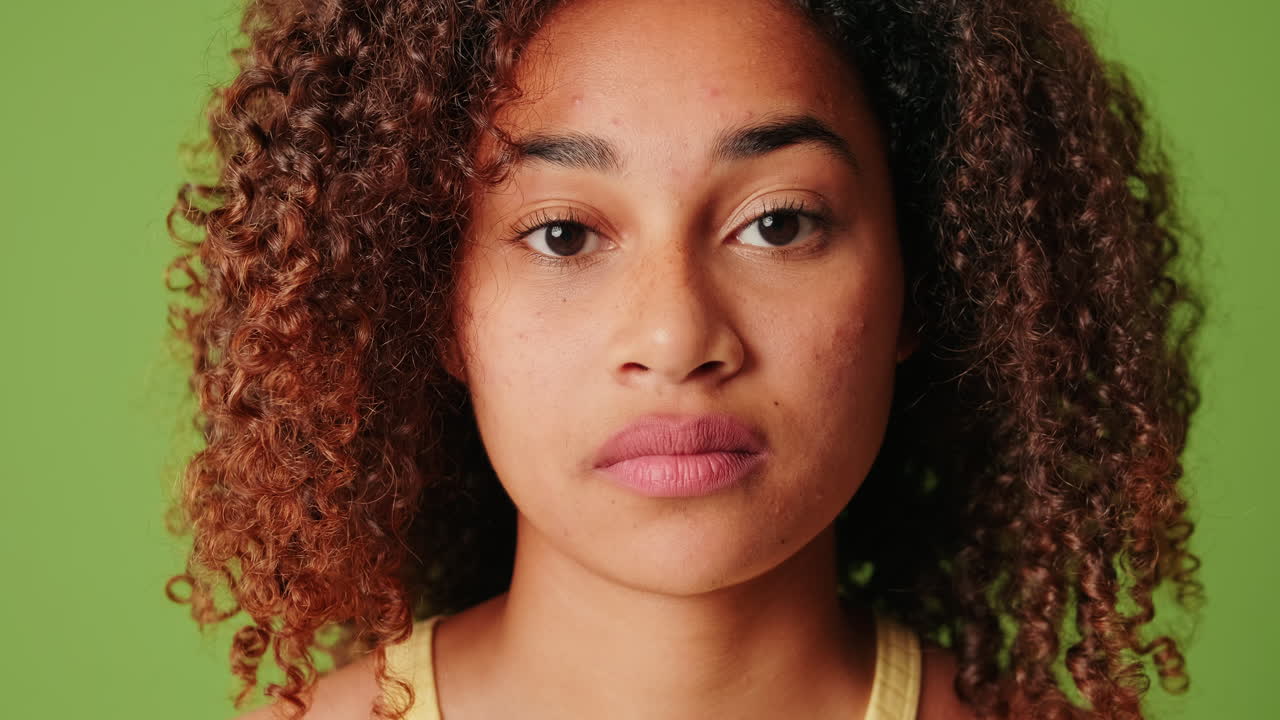 Young Mixed Race Woman with Neutral Expression Blinking on Green Screen