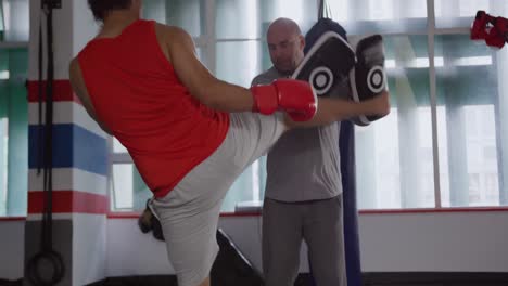 hombre caucásico entrenando con el entrenador en el gimnasio de boxeo